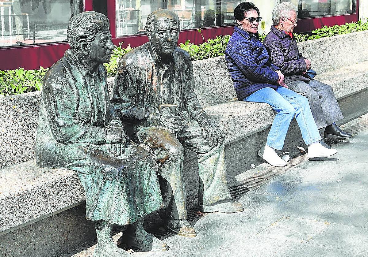 Dos mujeres sentadas al lado del Monumento a los Mayores, en un banco del Parque del Salón.