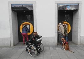 Varias personas sacan dinero de los cajeros automáticos de una entidad financiera.