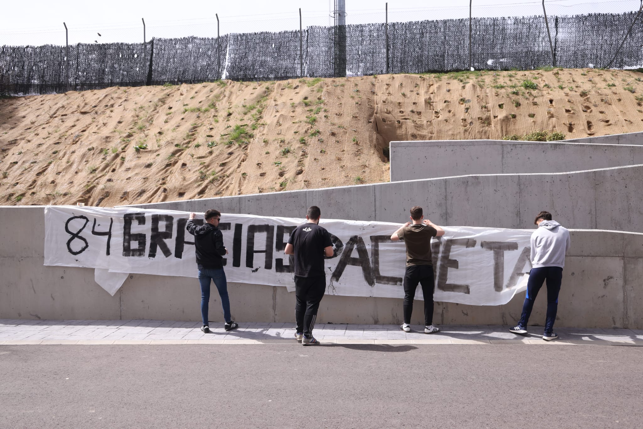 Un grupo de aficionados cuelga la pancarta.