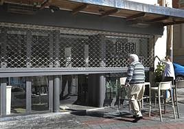 El bar Don Jamón sube la persiana metálica que protege el establecimiento.