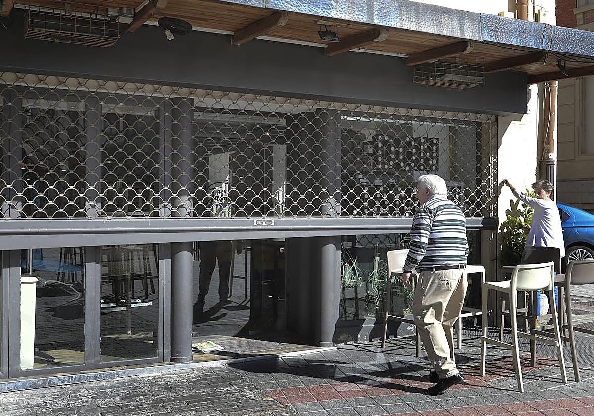 El bar Don Jamón sube la persiana metálica que protege el establecimiento.