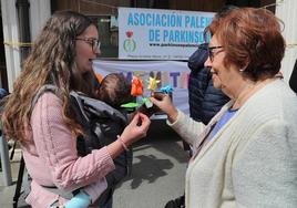 Socios de la Asociación Palentina de Parkinson entregan tulipanes como símbolo de la enfermedad, este martes en la Bocaplaza.