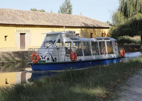 Imagen secundaria 1 - La embarcación Juan de Homar en el Canal de Castilla, a su paso por Frómista. A la derecha, visita de la a presidenta de la Diputación el mes pasado el nuevo edificio de Turismo, en el antiguo Juzgado Penal. 