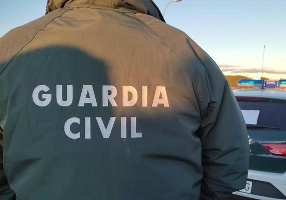 Un guardia civil delante de su coche patrulla.