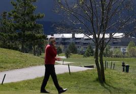 Un hombre habla por teléfono durante un recorrido por el campo de golf, con viviendas construidas en Quinta Real al fondo.