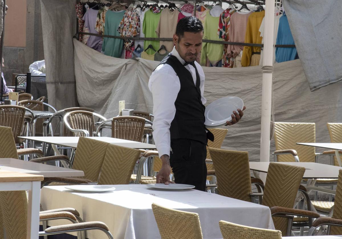 Un camarero prepara una mesa en la terraza de un céntrico restaurante segoviano.