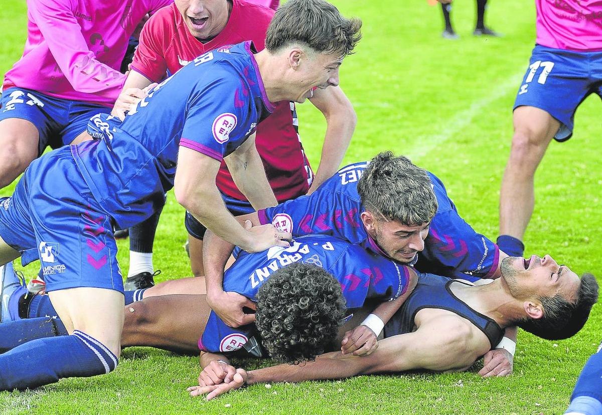 Jugadores de la Segoviana abrazan a Diego Gómez, en el suelo, tras el gol de la victoria ante el Socuéllamos.