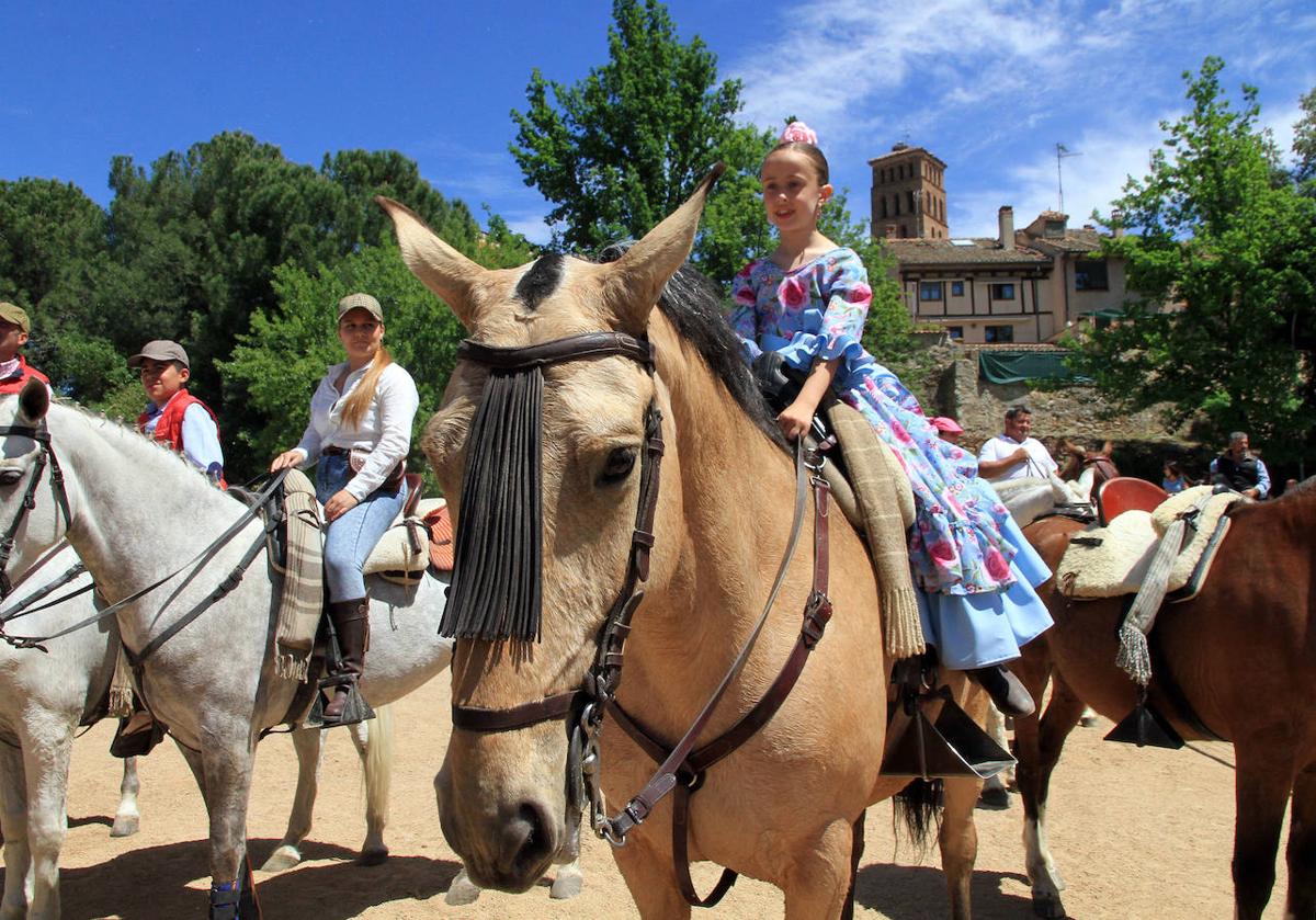 Una niña vestida de flamenca y subida en un caballo, durante la ruta por San Lorenzo.