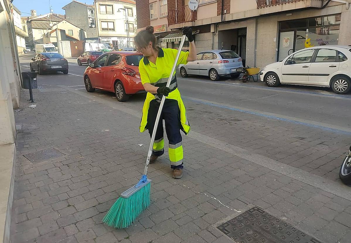 Una trabajadora del servicio municipal barre una calle de la localidad cuellarana.