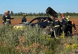 Los Bomberos de León, con el coche accidentado en el lugar del siniestro.