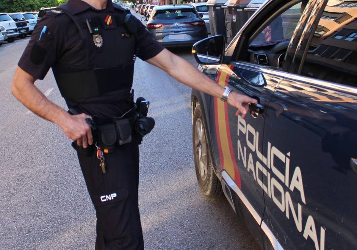 Un agente de la Policía Nacional junto a un coche patrulla.