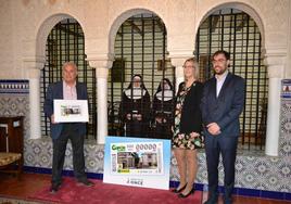 El alcalde de Astudillo, Luis Santos, sostiene una reproducción del cupón, acompañado de representantes de la ONCE, en el convento de Santa Clara.