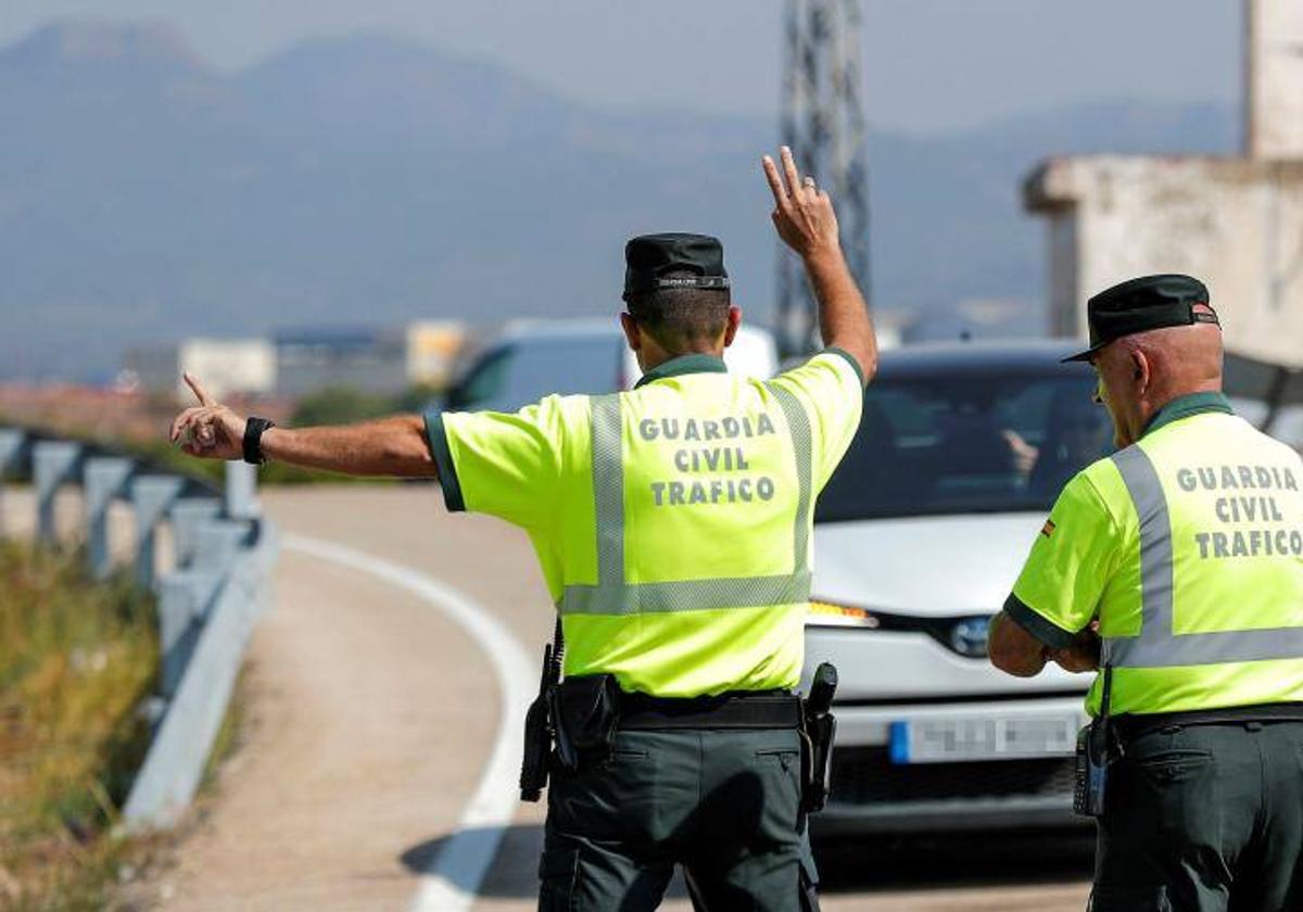 Un agente de la Guardia Civil de Tráfico da el alto a un vehículo durante un control de velocidad.