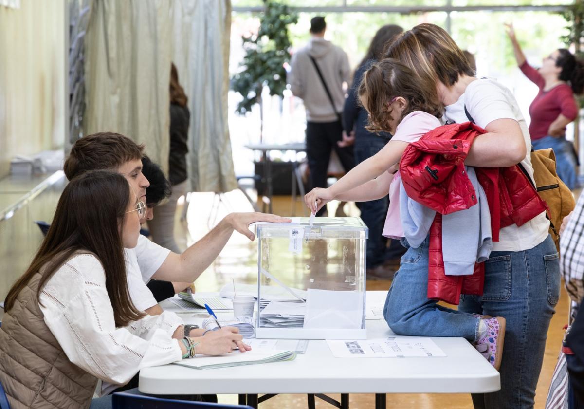 Una niña introduce el voto de su madre en una urna del Centro cívico Zona Este.