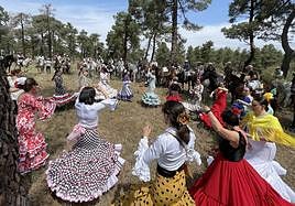 Mujeres vestidas con trajes de flamenca y caballistas, en un momento de la feria.