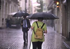 Dos viandantes se protegen de la tormenta caída el miércoles, en la calle Montero Calvo.