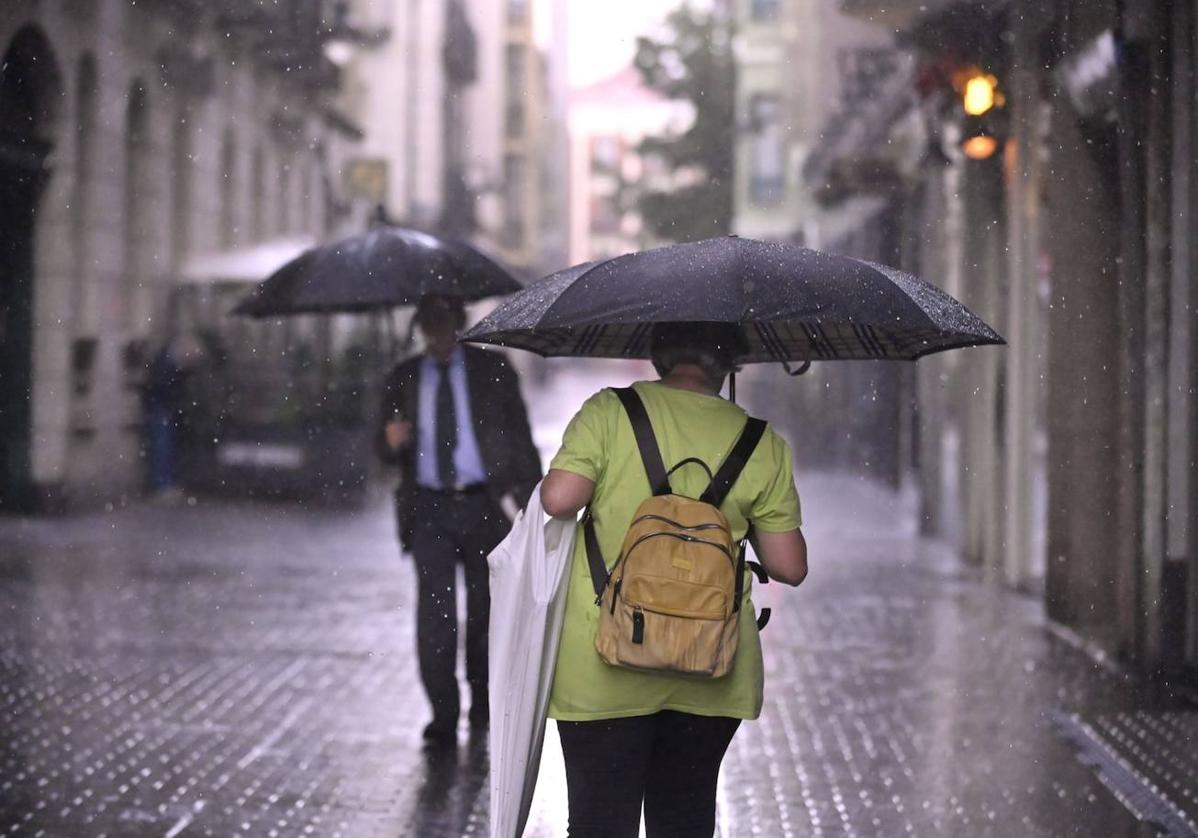 Dos viandantes se protegen de la tormenta caída el miércoles, en la calle Montero Calvo.