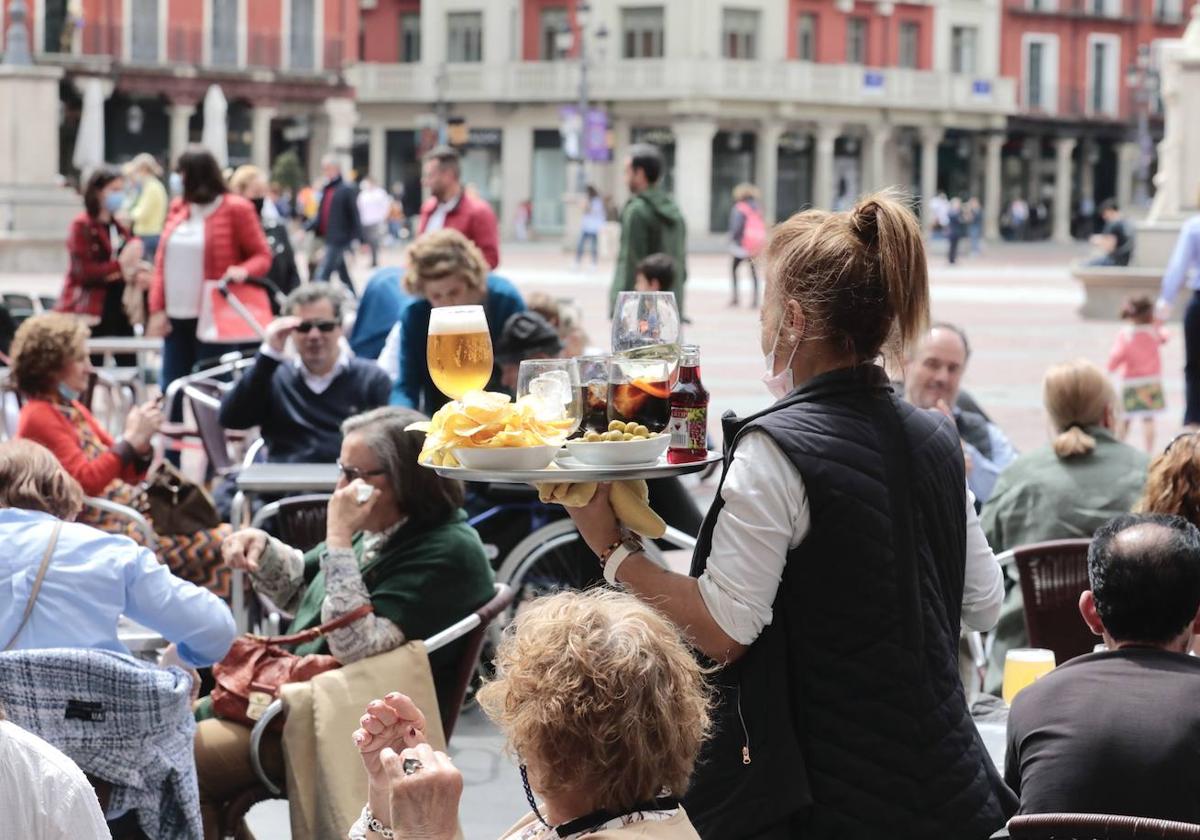 Una camarera sujeta una bandeja en una terraza de la Plaza Mayor.