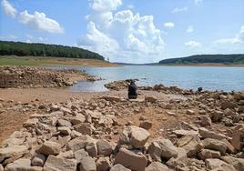 Una mujer descansa en las piedras del desaparecido pueblo de Frontada, a la vista por la sequía del pantano de Aguilar.