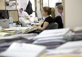 Funcionarios rodeados de expedientes pendientes de tramitación.