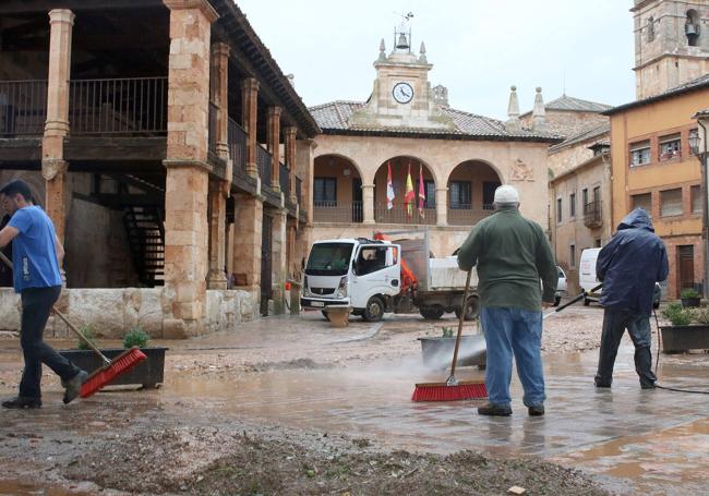 Vecinos limpian el barro de la tormenta en la plaza de Ayllón.