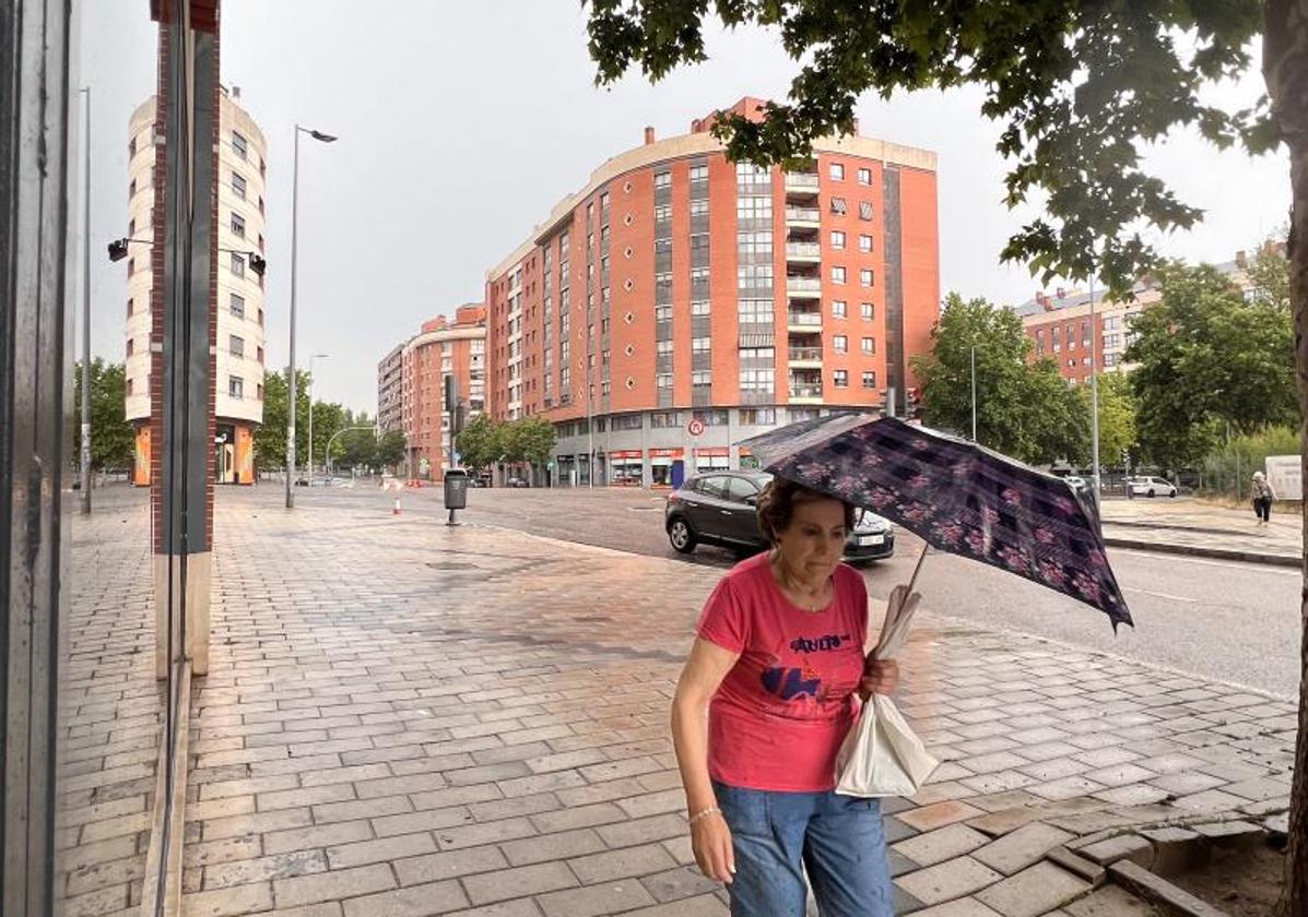 Una mujer se protege de la lluvia en Parquesol.