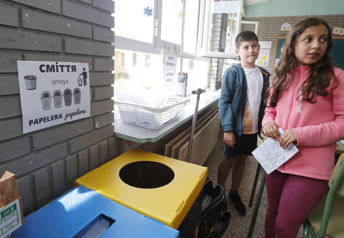 Dos alumnos de cuarto de Primaria del CEIP Alonso Berruguete, delante de un cartel para reciclar en castellano y ucraniano.