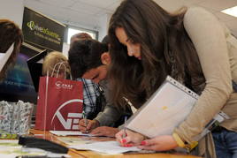 Jóvenes dejan currículos en una feria de empleo.