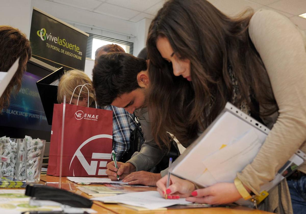 Jóvenes dejan currículos en una feria de empleo.