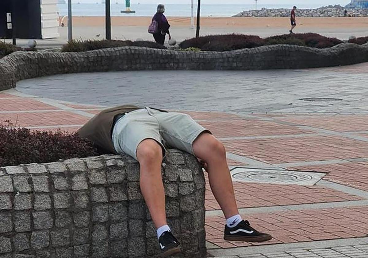 El hombre dormido sobre una jardinera instantes antes de que le despertaron los agentes.
