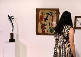 Una visitante ante la pintura 'Objeto', de Joan Miró, y esculturas creadas con materiales de desecho.