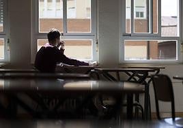 Un adolescente observa la calle desde la ventana de su clase.