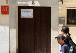 Dos turistas asiáticos pasan por delante de un inmueble de apartamentos turísticos acreditado, como señala la placa de la puerta.