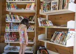 Una niña elige un libro para leer en una de las casetas.