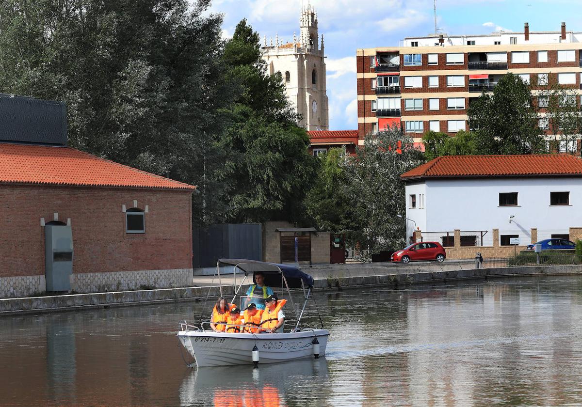 Un abuelo y sus nietos disfrutan de un paseo en barco por la dársena del Canal de Castilla.