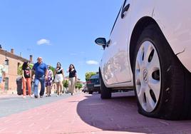 Varios vecinos de Alaejos caminan por delante de uno de los coches afectados por los actos vandálicos.