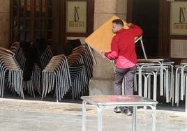 Un camarero despliega la terraza a primera hora de la mañana en la avenida del Acueducto.