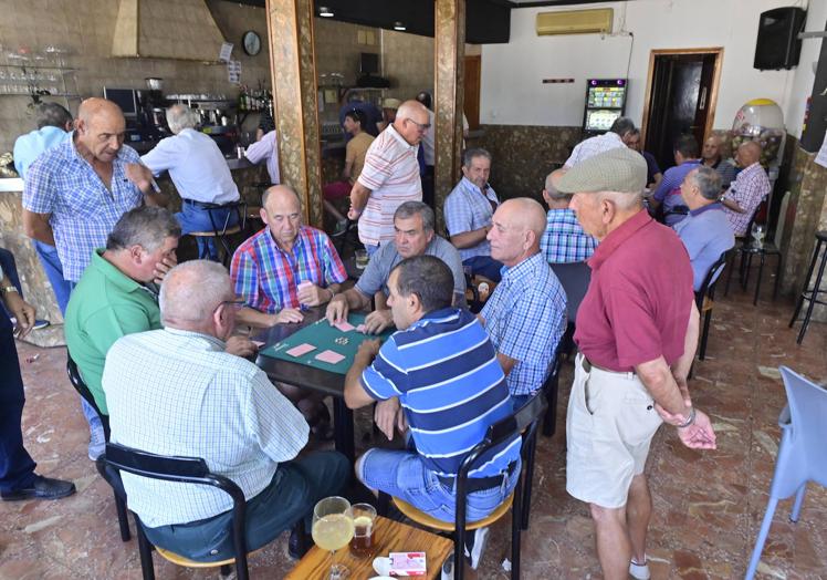 Imagen principal - El segundo premio de la Lotería no interrumpe la partida de mus en Ataquines. Javier Sanz muestra su décimo y detalle del 21.162 en las manos de Florentino Fernández.