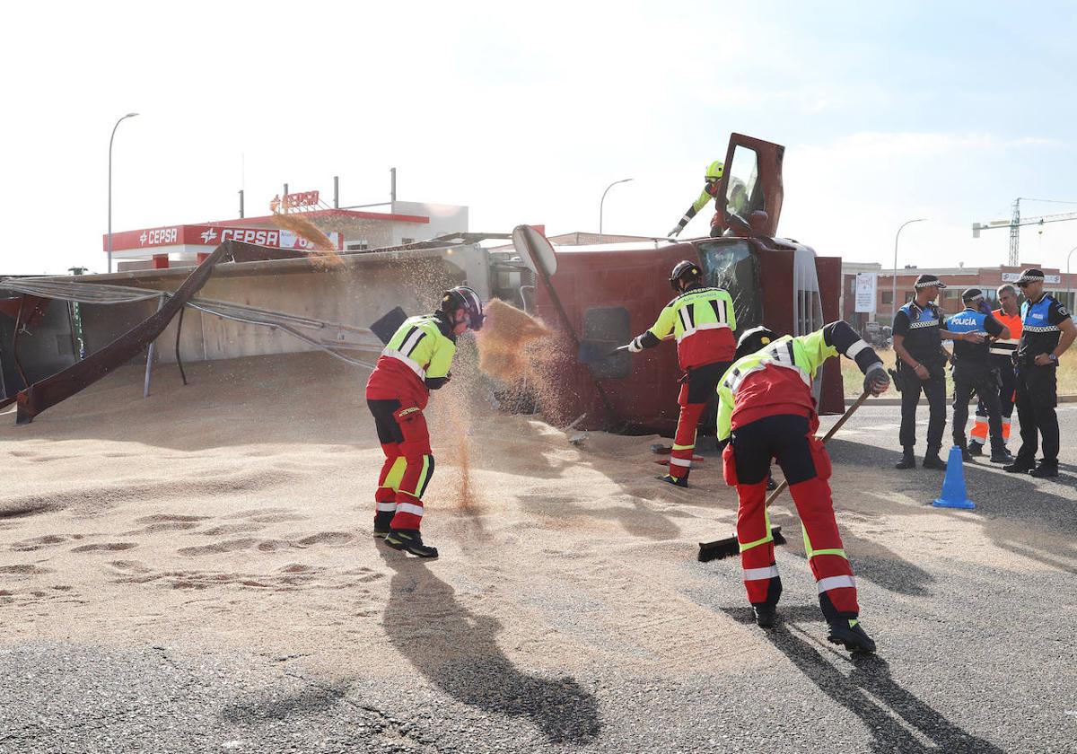 Los bomberos ayudan a retirar la carga del camión volcado.