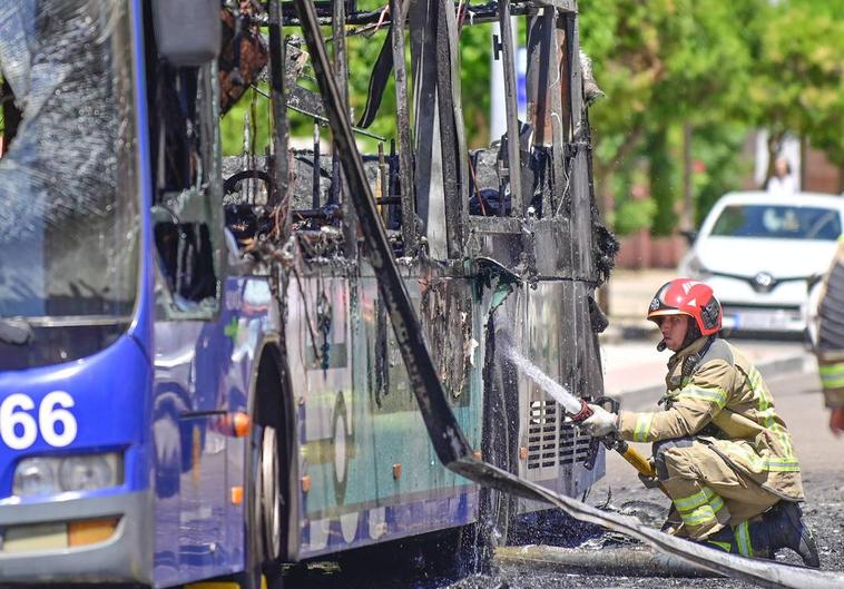 Un bombero remata las labores de extinción del autobús calcinado en Pío Baroja.