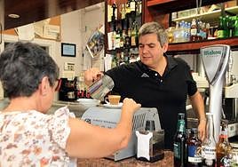Luis Muñoz, del bar California, sirve un café a una clienta.