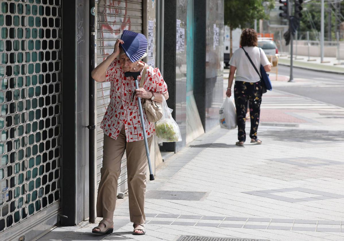 Una mujer se protege del sol con su abanico.