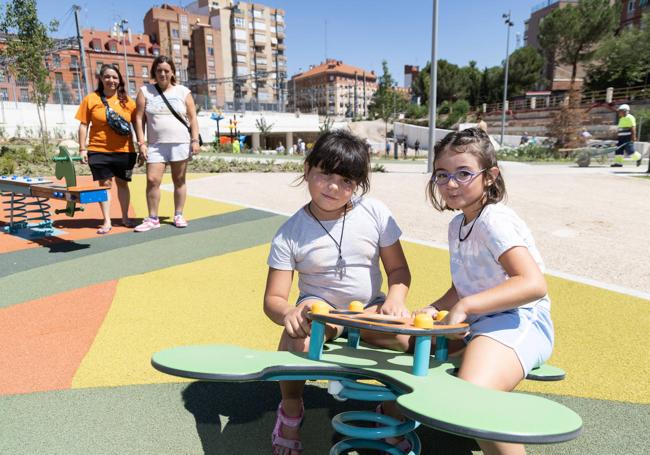 Alba y Elsa, en un columpio, delante de su smadres, Alba María y Sonia.