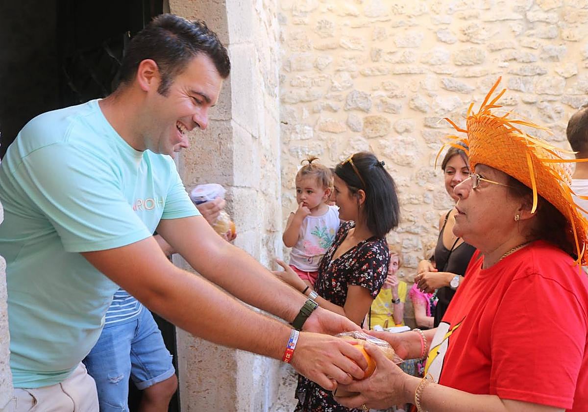 El alcalde de Herrera de Valdecañas entrega pan con chocolate y una naranja a cada vecino como marca la tradición.