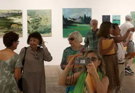 Algunos asistentes a la inauguración de este jueves admiran y fotografían las obras de los pensionados.