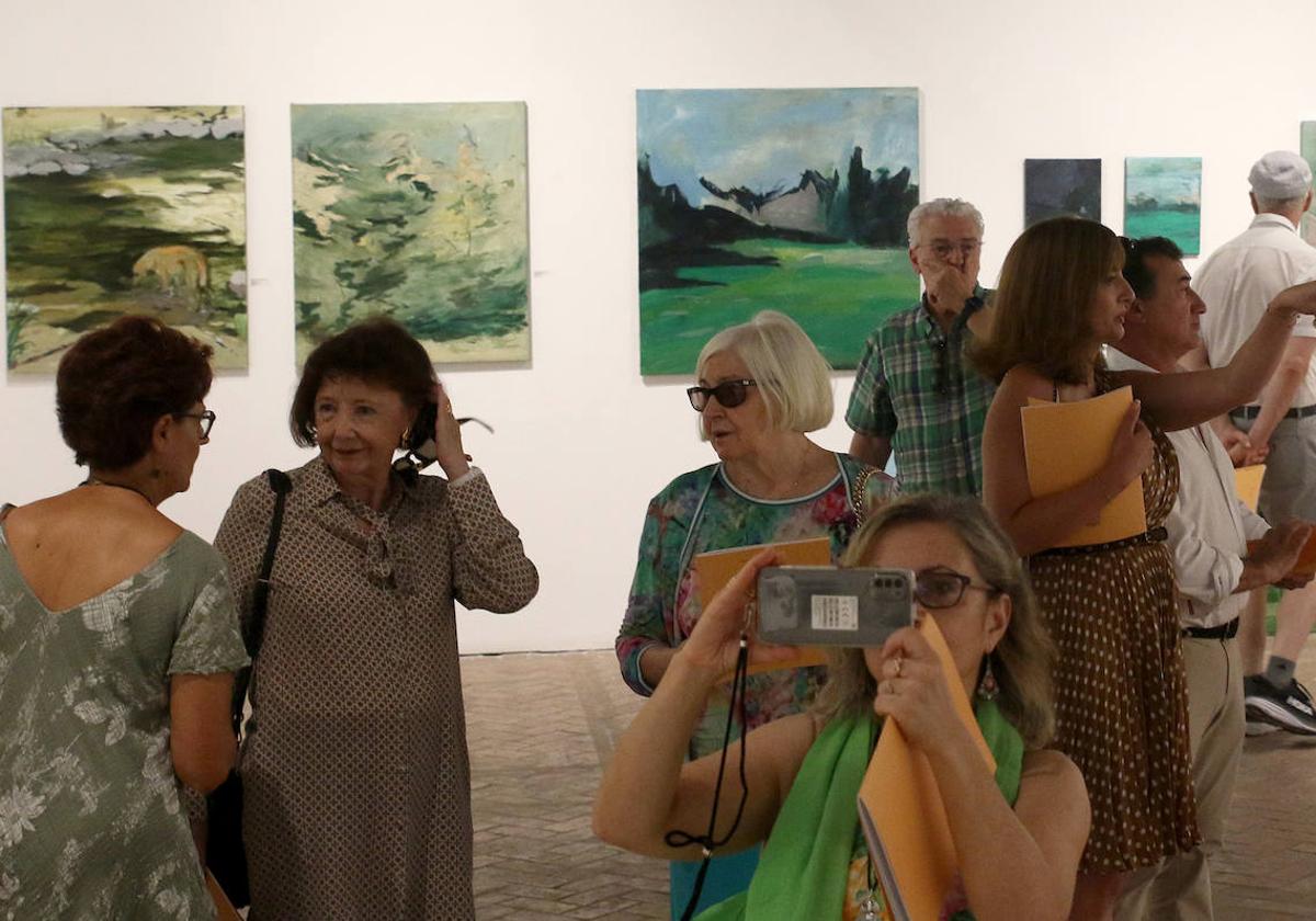 Algunos asistentes a la inauguración de este jueves admiran y fotografían las obras de los pensionados.