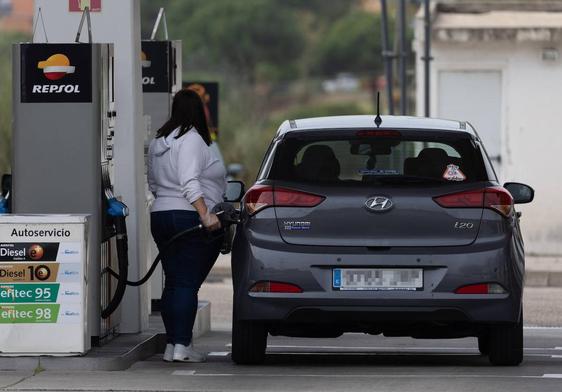 Una mujer echa gasolina en su coche.