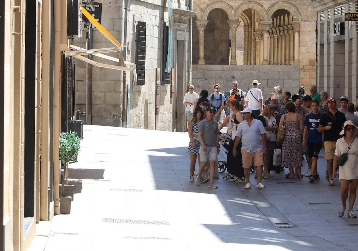 Decenas de personas caminan por la zona de sombra de la Calle Real de Segovia.