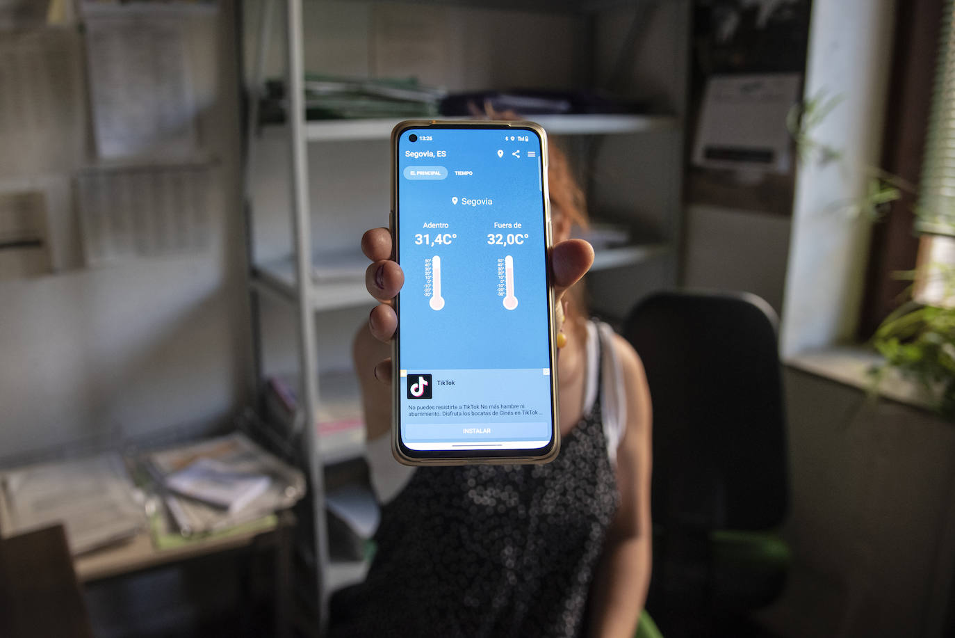 Trabajadora de la Audiencia muestra el móvil con la temperatura en el interior y el exterior del edificio, en ambos casos superior a los 32 grados.