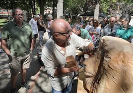 El escultor Alfredo Martín 'Chis' talla la cabeza de un león ante la mirada del público.